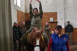 A Ukrainian servicewoman rides a horse during a hippotherapy session in Kyiv