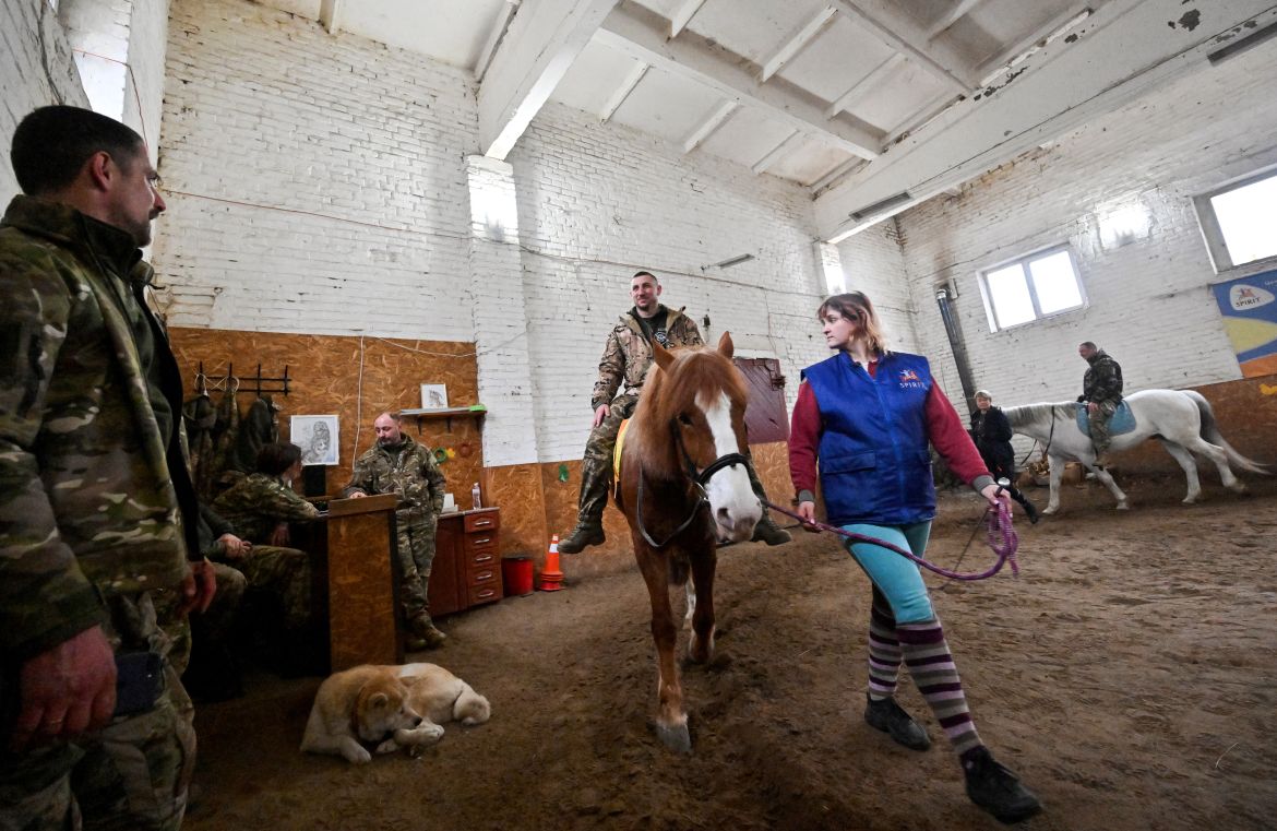A Ukrainian serviceman rides a horse during a hippotherapy session in Kyiv