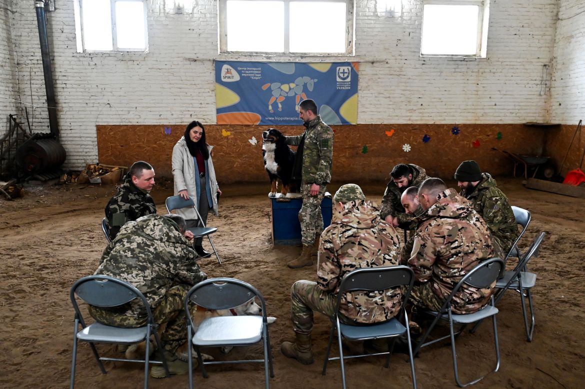 Ukrainian servicemen play with dogs during a hippotherapy session in Kyiv