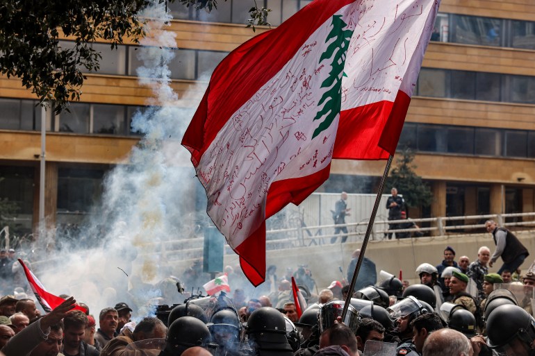 Seorang pengunjuk rasa mengibarkan bendera nasional Lebanon