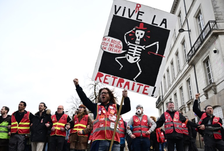 Protestors hold a sign reading "We've got a job, it's not to die for" during a demonstration, a week after the government pushed a pensions reform through parliament without a vote, using the article 49.3 of the constitution, in Nantes, western France, on March 23, 2023.