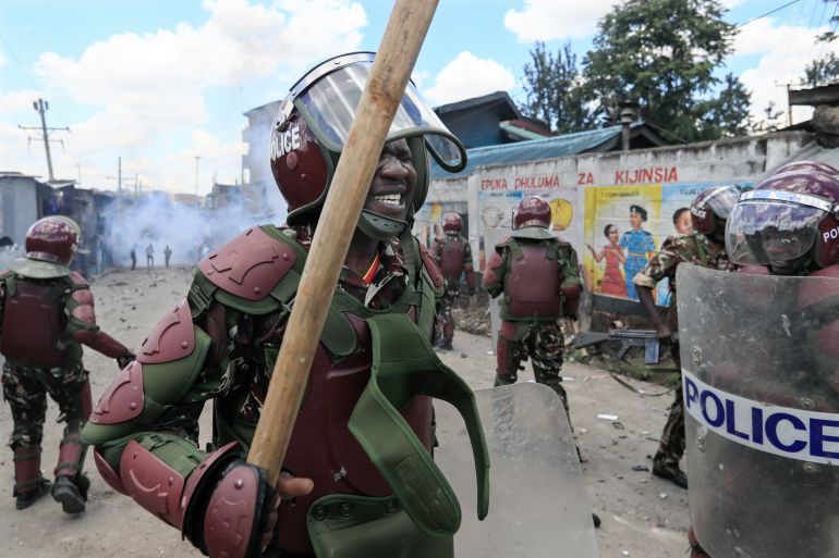 Anti-riot police officers react to the effects of tear gas after one of their canisters fired at protesters was lobbed back at them during confrontations at a mass rally called by opposition leader Raila Odinga, in Mathare, Nairobi, on March 27, 2023 [Tony Karumba / AFP]