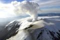 A snowy volcanic peak with smoke pouring out