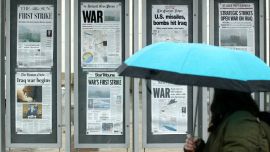 Newspapers on a wall, showing headlines about the Iraq war