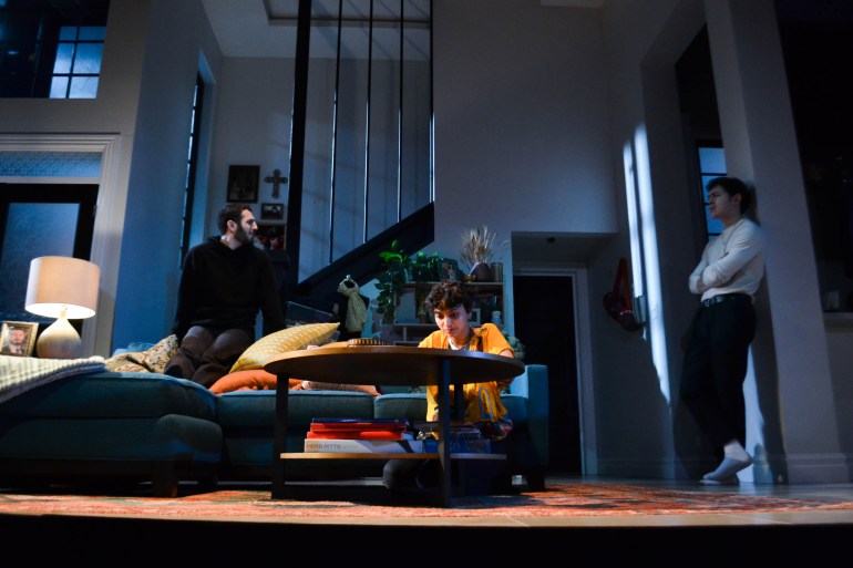Three actors rehearse on a stage set made to look like a house