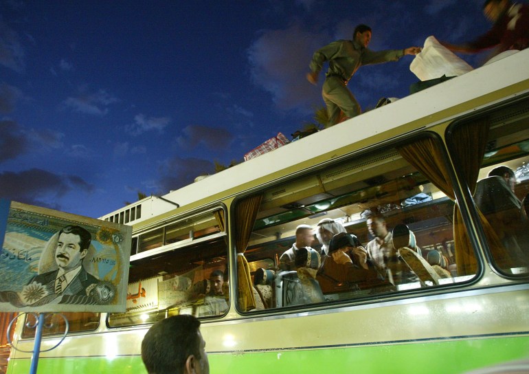 An Iraqi man looks at his mother in a bus as others load luggage on the top of the vehicle