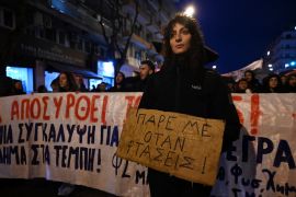 A woman holds a placard that reads "Call me when you arrive" during a protest in the port city of Thessaloniki, northern Greece
