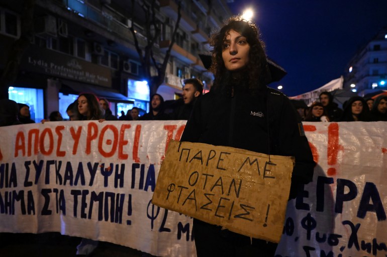 A woman holds a placard that reads: 