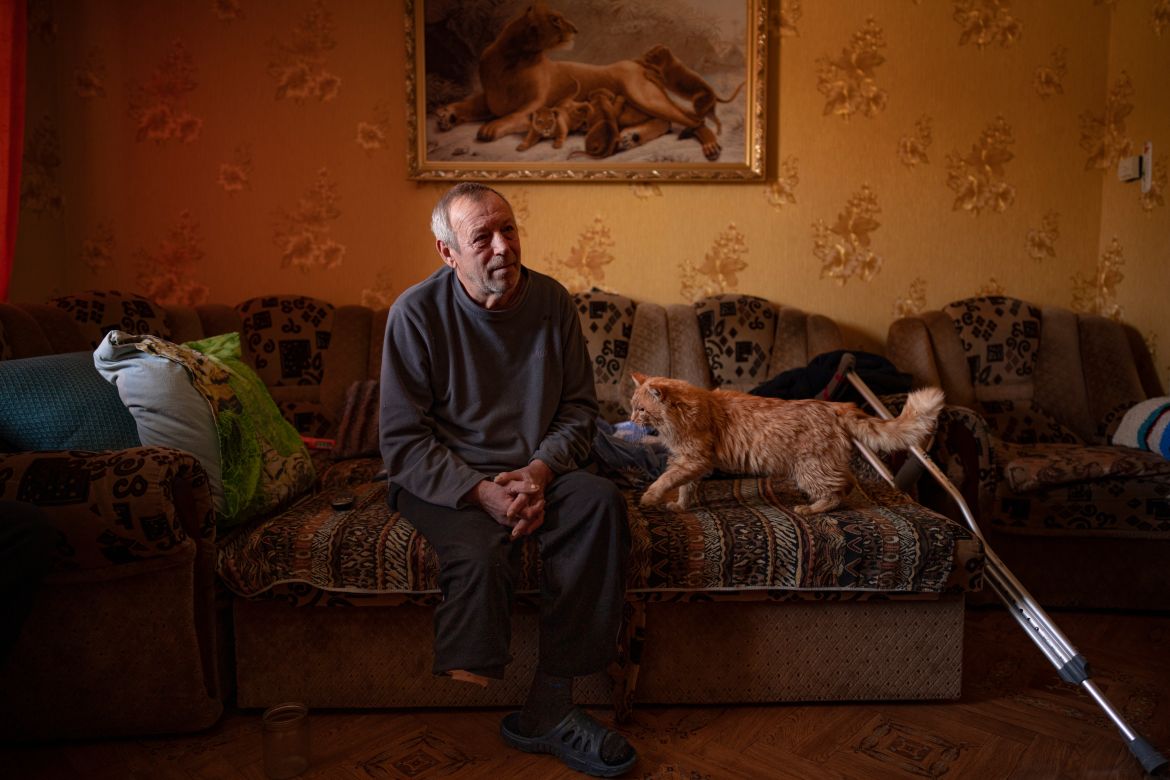 Land mine victim Oleksandr Rabenko, 66 years-old, speaks during an interview with the Associated Press as Murzik, his cat, approaches, at his son's home on the outskirts of Izium
