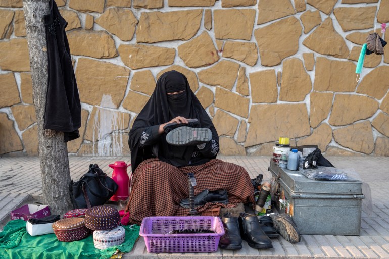 An Afghan woman cleans the shoes of a customer on the street in Kabul, Afghanistan, March 5, 2023. [Ebrahim Noroozi/AP Photo]