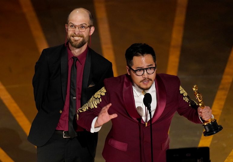Two men gesture excitedly on stage at the Oscars