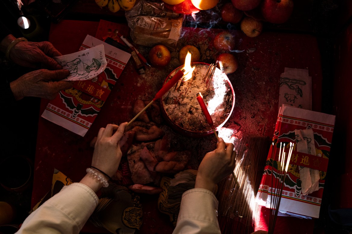 A customer burns incense sticks during a "villain hitting" ceremony on the day of "ging zat," as pronounced in Cantonese, which on the Chinese lunar calendar literally means "awakening of insects,"