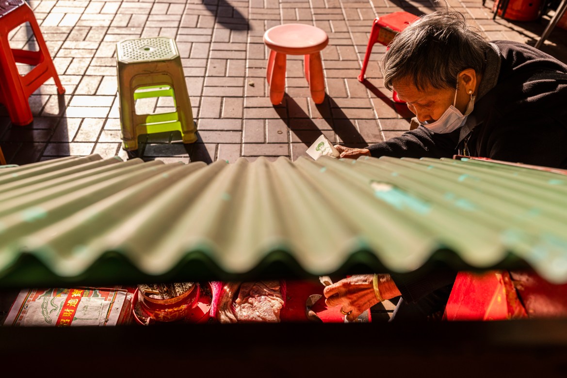 A practitioner prepares papers with image of a villain at a "villain hitting" booth under the Canal Road Flyover in Hong Kong