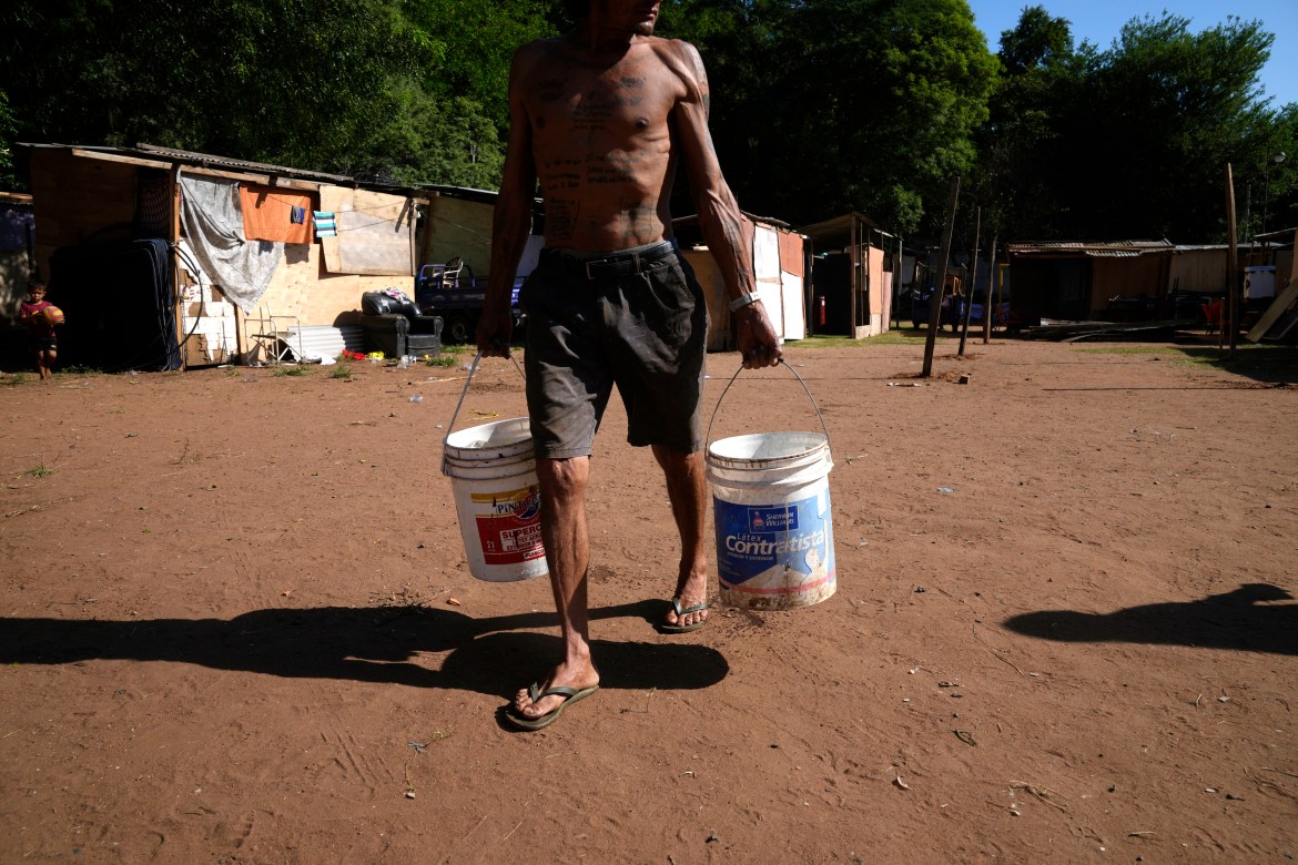 Carmelo Del Valle, who was displaced from his home by the rising waters of the Paraguay River, hauls buckets of water to his temporary shelter, in Asuncion, Paraguay