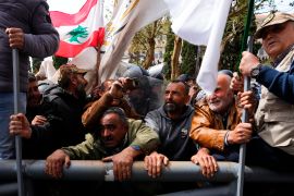Retired members of the Lebanese security forces and other protesters try to remove a gate in order to advance towards the government building during a protest demanding better pay in Beirut. [Hassan Ammar/AP Photo]
