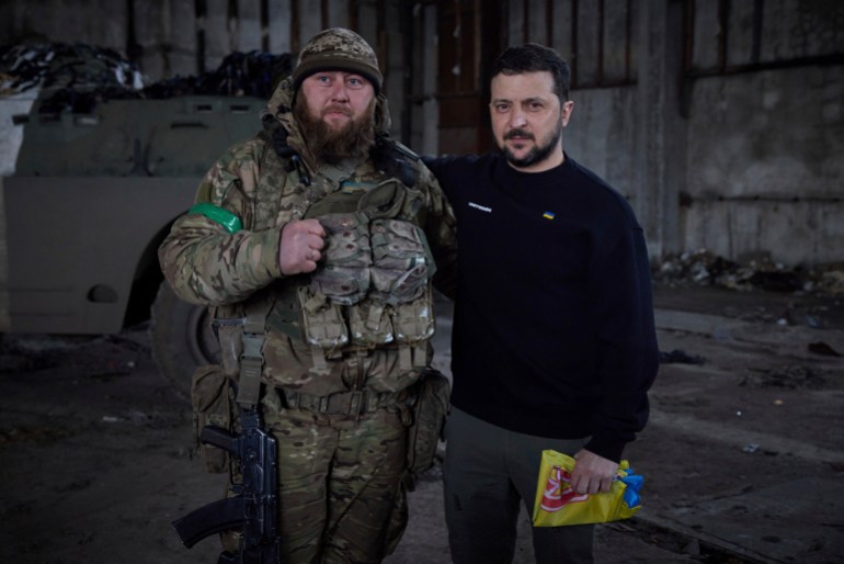 O presidente ucraniano Volodymyr Zelenskyy e um soldado posam para uma foto após uma cerimônia de premiação em uma posição perto de Bakhmut