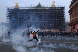 A protester kicks a tear gas canister in front of the Opera at the end of a rally in Paris [Aurelien Morissard/AP Photo]