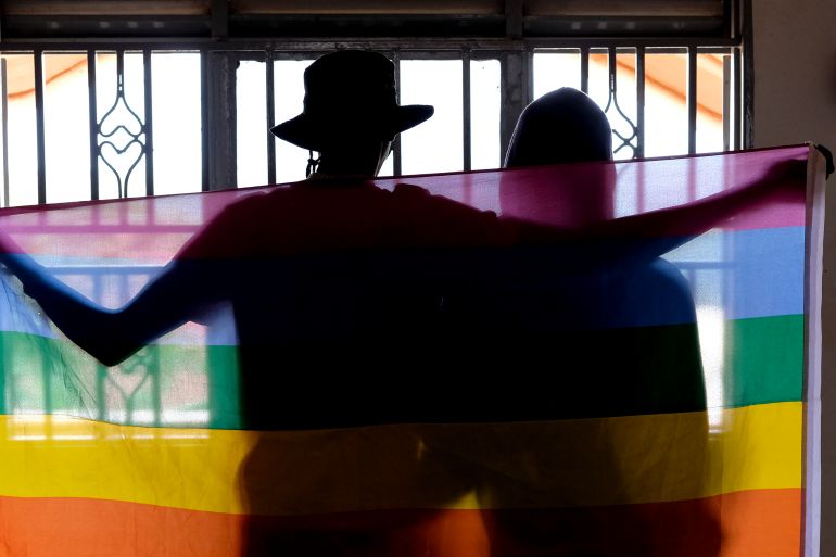 A gay Ugandan couple cover themselves with a pride flag
