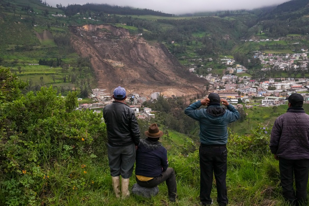 Residents look over the site of a landslide that buried dozens of homes in Alausi, Ecuador