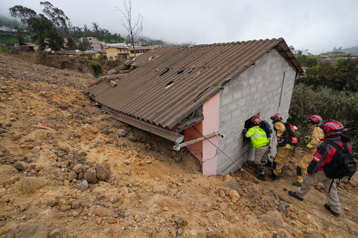 Rescue workers inspect a house destroyed by a deadly landslide that buried dozens of homes in Alausi, Ecuador