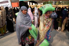 Women leave with their free sack of wheat flour at a distribution point in Lahore, Pakistan [File: K.M. Chaudary/AP Photo]