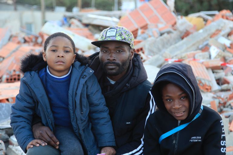 Adriano Kuzingami and his two children on the remains of their home, in Segundo Torrao [Ana Naomi de Sousa/Al Jazeera]