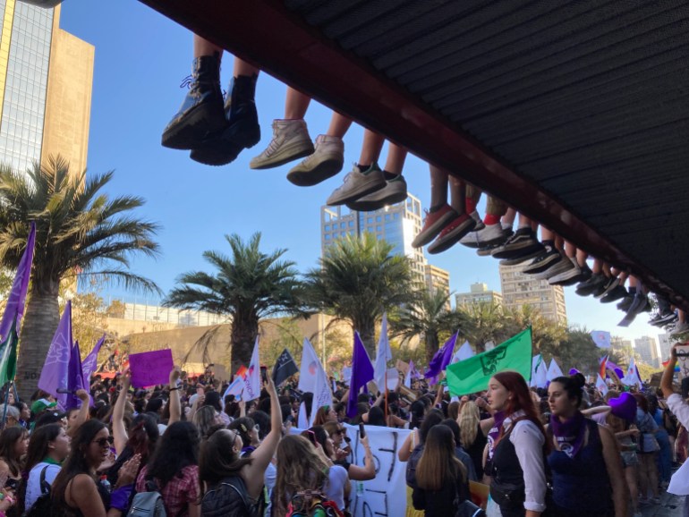 Protesters' feet dangle from the edge of a structure during a rally in Chile in support of abortion rights 