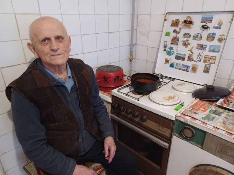 A photo of Ivan Capan sitting in front of his stove.