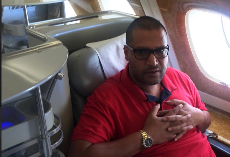 Mohamed Khan duduk di kursi pesawat. 