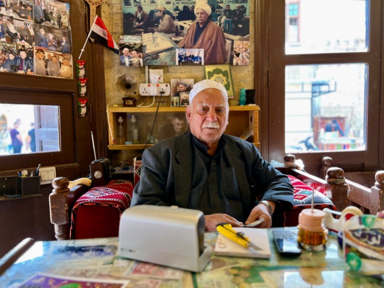 Haj Mohammed al-Khashali behind his desk with photos and mementos of the past behind him. 