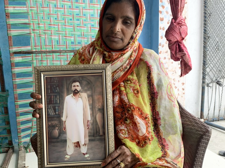 A photo of a woman holding a framed photo of a man.
