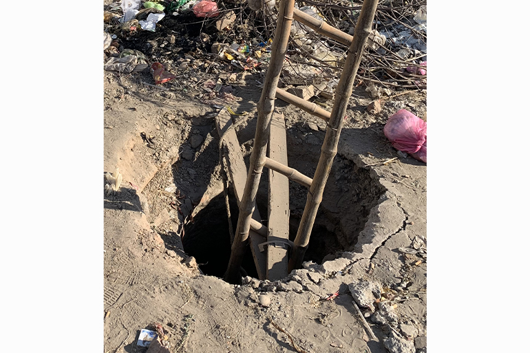 A photo of a hole in the ground with a ladder coming out of it.