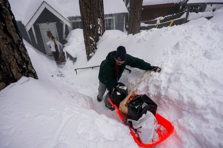 A resident hauls groceries into their home on a sled amid heavy snowfall