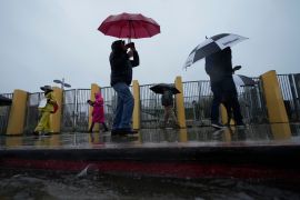 Workers carry umbrellas on a picket line in the rain in Los Angeles