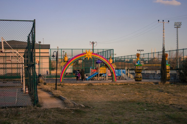 Playground at the community centre with a couple kids playing behind a rainbow decoration.