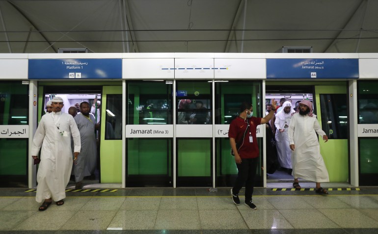 A railway usher gestures to Muslim pilgrims arriving on a Metro from Arafat area to Mina during the annual Hajj season in the western Saudi city of Mecca on August 22, 2018. - The Holy Sites subway light rail in Mecca was opened eight years ago. The Chinese-built monorail project, linking Mecca with the holy sites of Mina, Arafat and Muzdalifah, started operation in 2010 during the Hajj season to ferry Saudi nationals taking part in the annual Muslim pilgrimage. (Photo by AHMAD AL-RUBAYE / AFP)