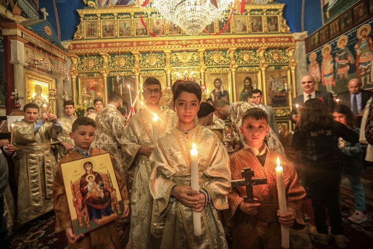 Anak laki-laki altar memegang lilin, salib, dan ikon di gereja