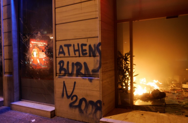 Sebuah bank yang ditandai dengan grafiti terbakar selama kerusuhan di Athena 8 Desember 2008. Para pengunjuk rasa membakar sebuah department store besar di pusat kota Athena dan membakar pohon Natal raksasa kota di luar parlemen saat protes anti-pemerintah memburuk.  REUTERS/John Kolesidis (YUNANI)