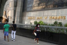 Local residents walk past the Reserve Bank of Zimbabwe