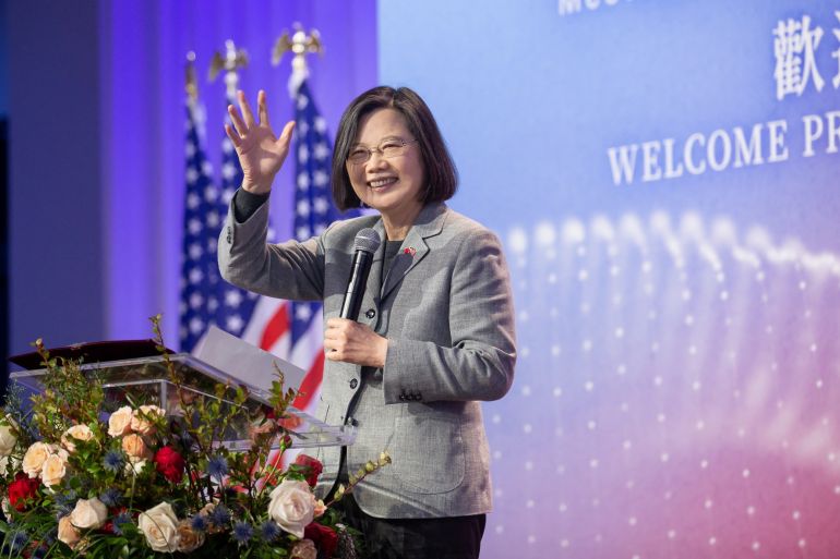 Taiwan President Tsai Ing-wen waves during a meeting in New York with the Taiwanese community. She is on a stage behind a lectern and smiling. There is a large sign at the back of the stage welcoming her.