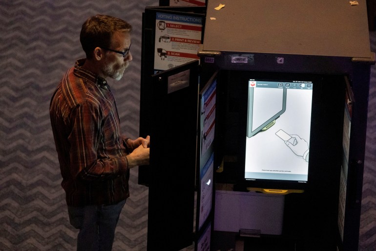Seorang pria memberikan suara di mesin pemungutan suara elektronik