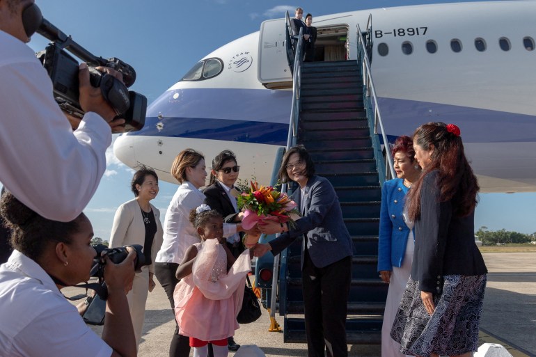 Tsai Ing-wen getting off her plane in Belize. She is receiving a bouquet at the bottom of the steps from the plane.