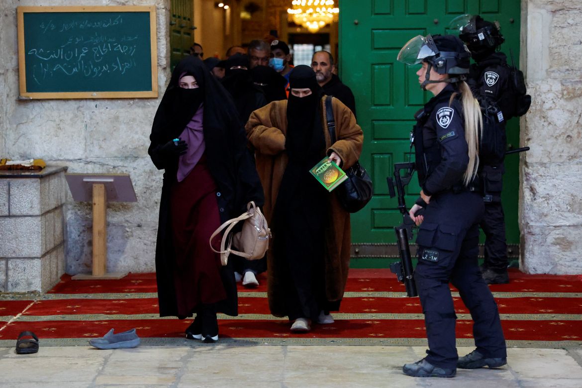 Palestinians walk out as Israeli security forces take position at the Al-Aqsa compound