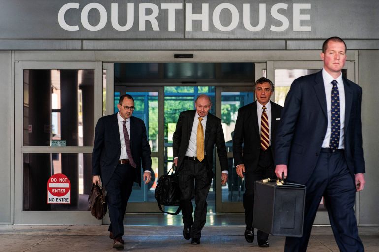 Men in suits exit sliding doors under the word "courthouse"