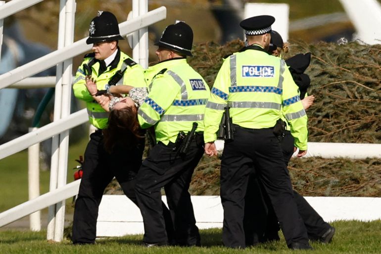 An animal rights activist is apprehended by police officers at Aintree Racecourse