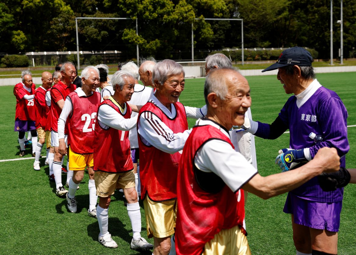 Red Star’s midfielder Mutsuhiko Nomura, 83, and White Bear’s goalkeeper Shingo Shiozawa, 93, greet their opponents at the SFL (Soccer For Life) 80 League opening match