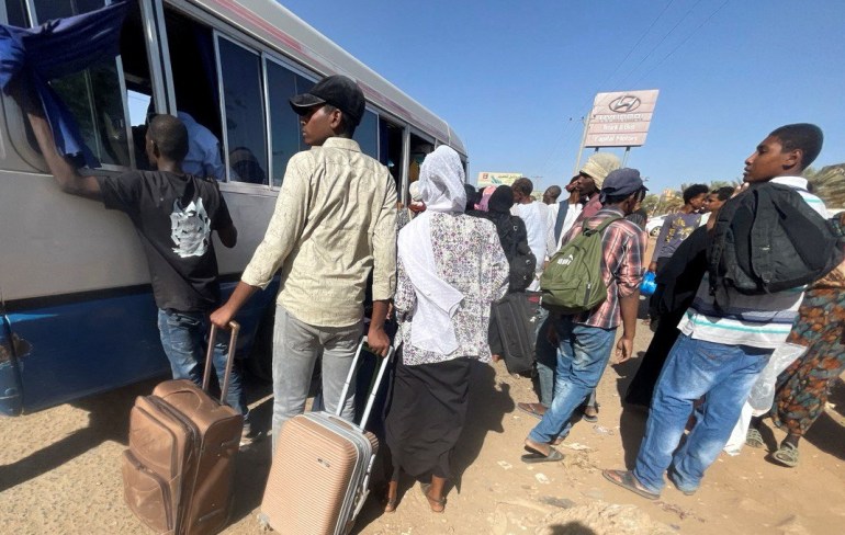 احتشد الناس حول حافلة في الخرطوم أثناء فرارهم من المدينة.  لديهم حقائب معهم.