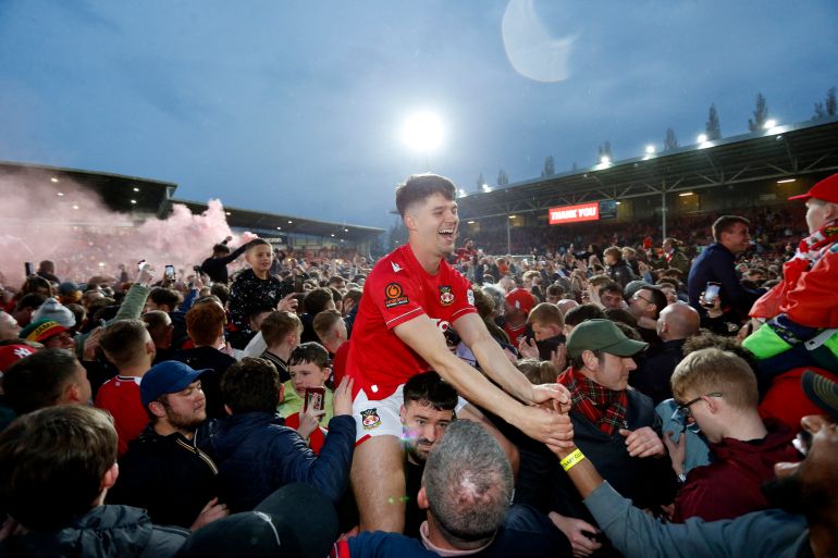 Wrexham's Jordan Davies celebrates with fans on the pitch after the match as Wrexham win the National League and promotion to League Two