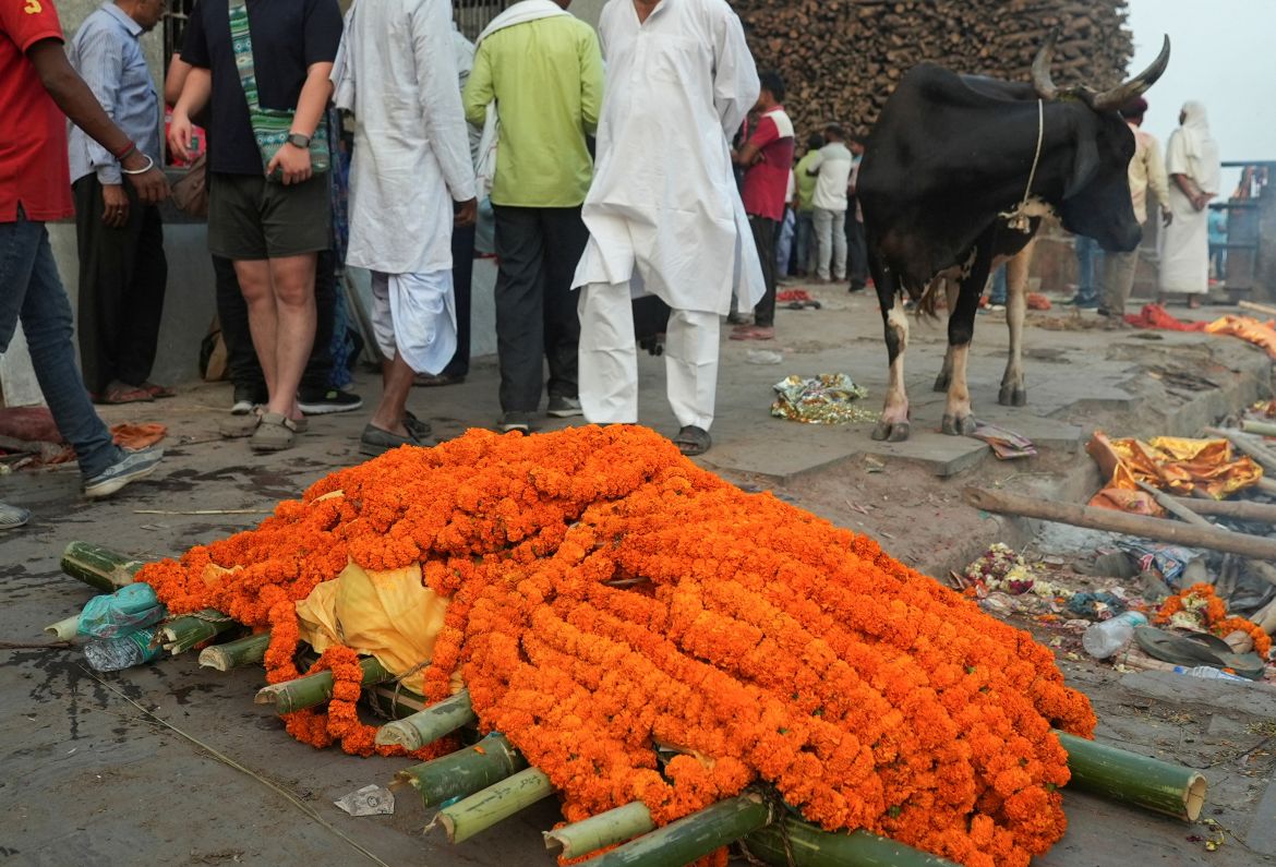 People stand next to a bier being prepared for cremation at Manikarnika Ghat, an ancient crematorium lying on the shores of the Ganges, in Varanasi,