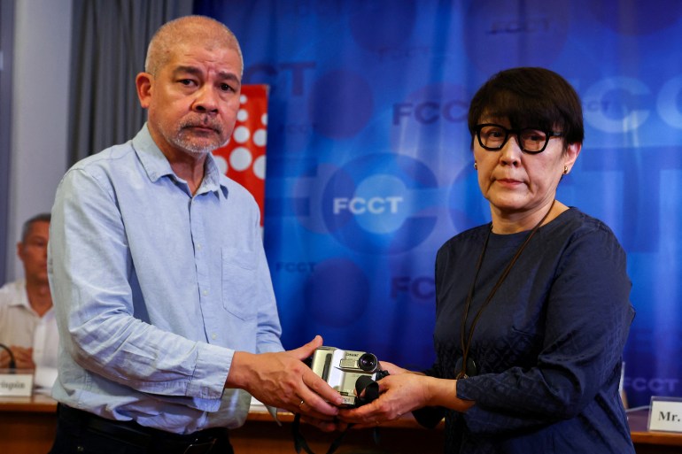 Noriko Ogawa, sister of slain Japanese journalist Kenji Nagai, receives her brother's lost video camera from Aye Chan Naing, co-founder of the Democratic Voice of Burma (DVB), at an event to release unseen footage he filmed before he was killed during coverage of the 2007 saffron revolution in Yangon at the Foreign Correspondent's Club of Thailand in Bangkok, Thailand, April 26, 2023. REUTERS/Athit Perawongmetha